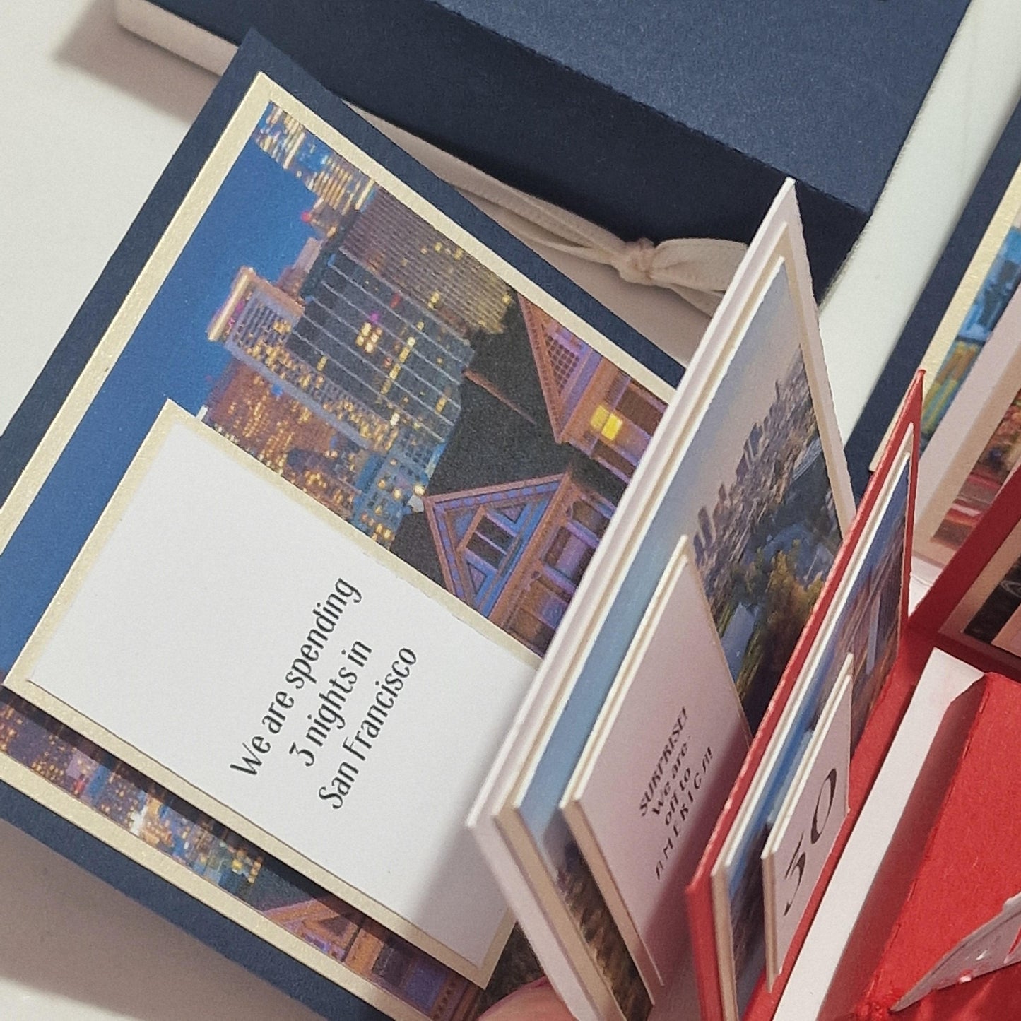 Exploding Occasions Box - Trip Reveal AMERICA featuring a city-themed book and decorative cards, designed for a multi-stop American road trip surprise with iconic architecture and customizable details.