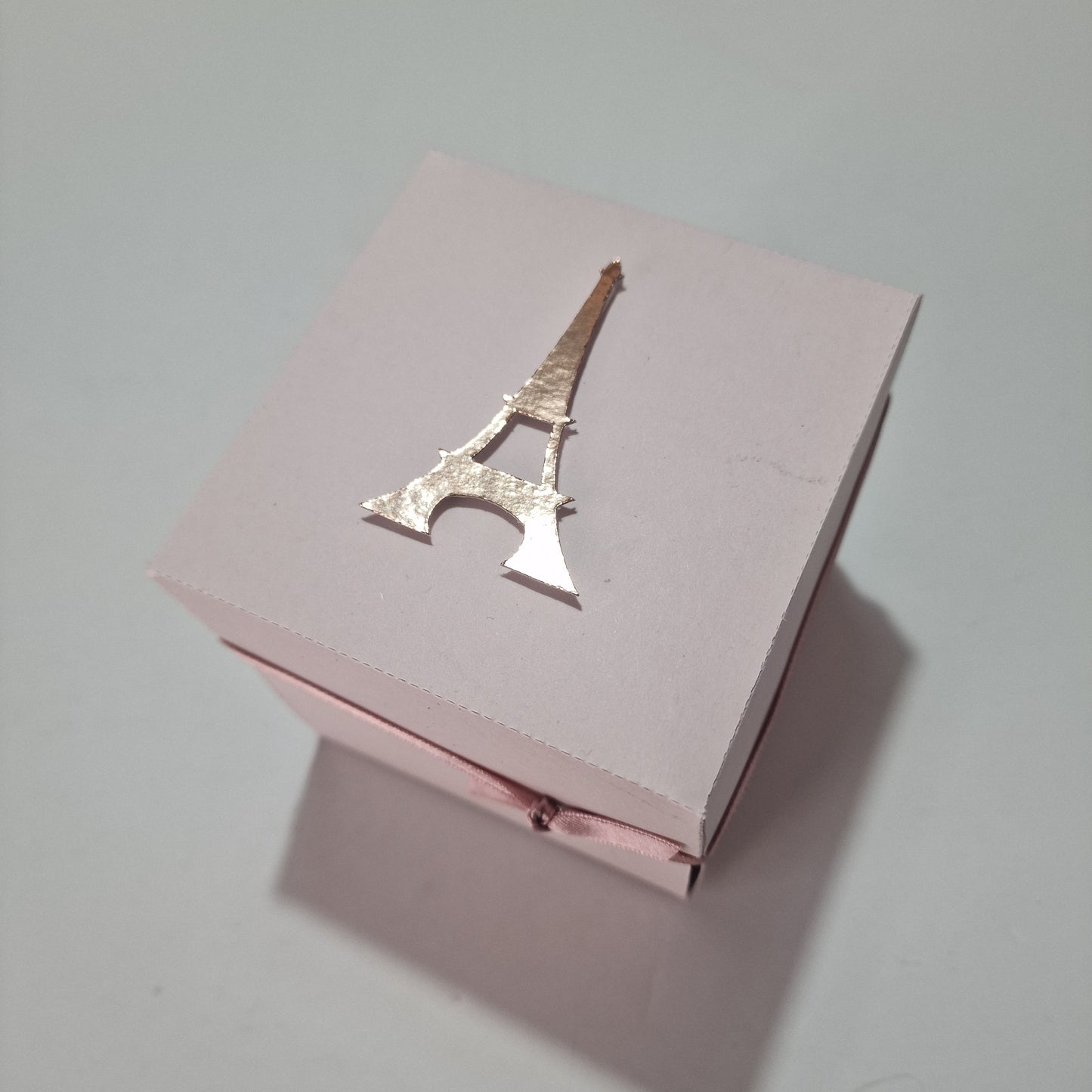 Paris - Special Occasion Celebration Trip Reveal Explosion Box featuring a gold Eiffel Tower centerpiece, resembling a surprise gift box with intricate paper and architectural panels, perfect for a Paris-themed event.