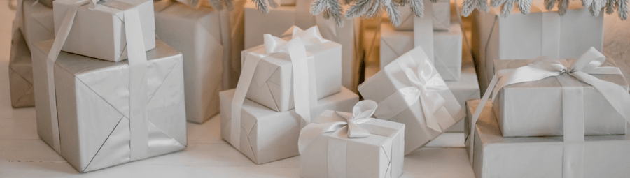 Silver Christmas presents under a decorated tree with lights.