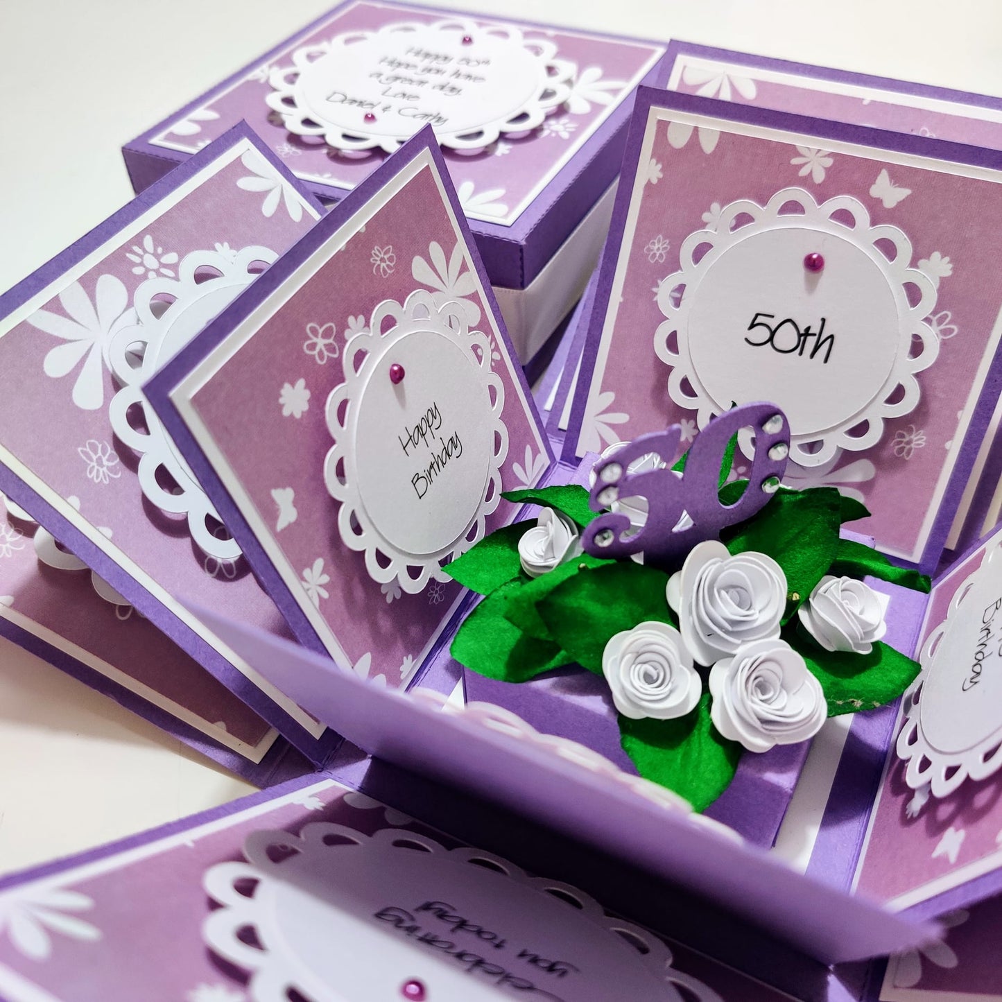Lilac & White Roses Birthday Celebration Pop-Open Box Card featuring an intricate pop-up design with roses, perfect for birthdays. The card is designed to open dynamically, revealing a festive floral arrangement.