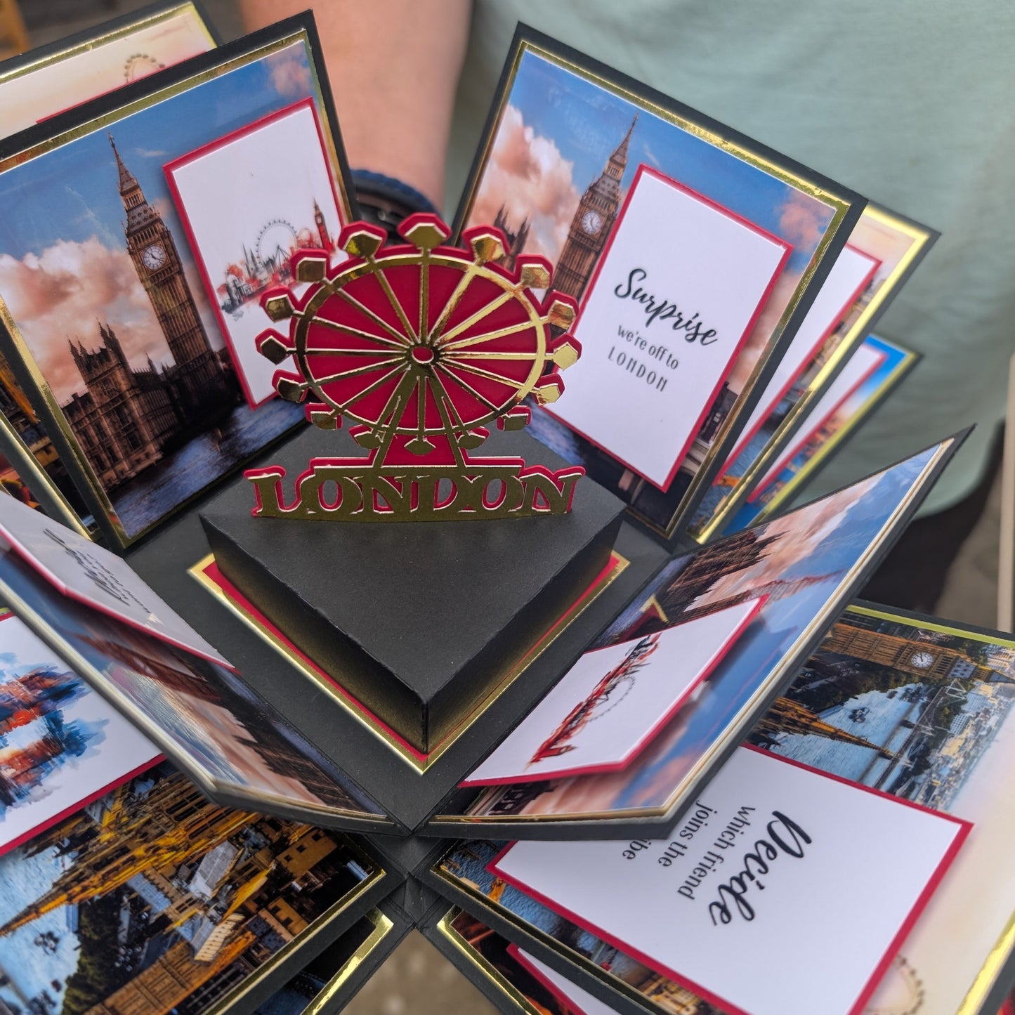 London - Special Occasion | Celebration Trip Reveal Explosion Box: A 3D pop-up gift card with iconic London landmarks and message cards, featuring a red-and-gold London Eye centerpiece announcing a surprise trip.