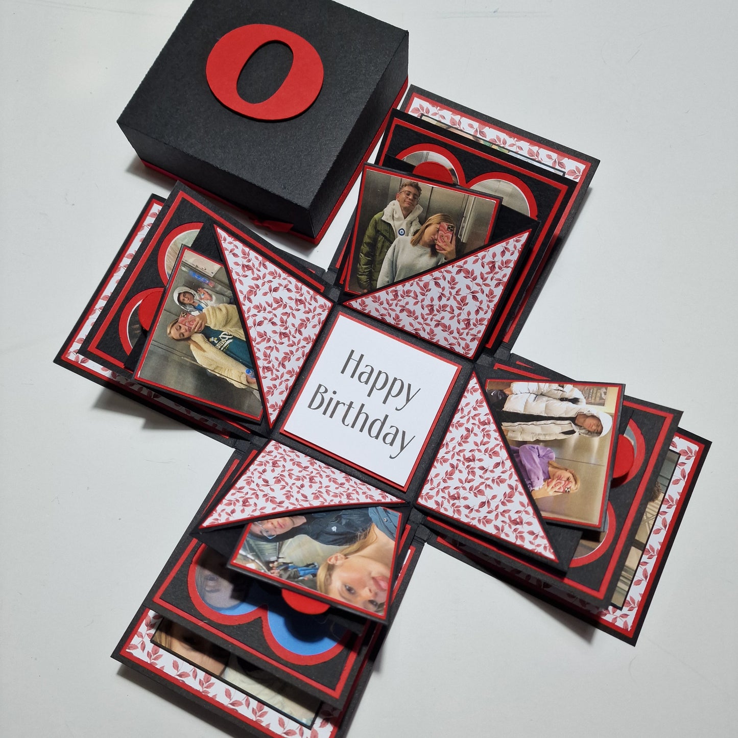 Exploding Memory Photo Box - Black & Red Leaves: A handcrafted box with layered photo panels and red leaf-patterned embellishments, featuring triangular compartments for notes and a “Happy Birthday” centerpiece.