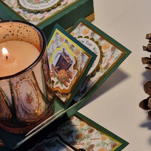 Vintage styled Christmas Candle Box featuring a candle in a glass holder next to a pine cone, perfect for holiday decor or gifting with three festive fragrance options.
