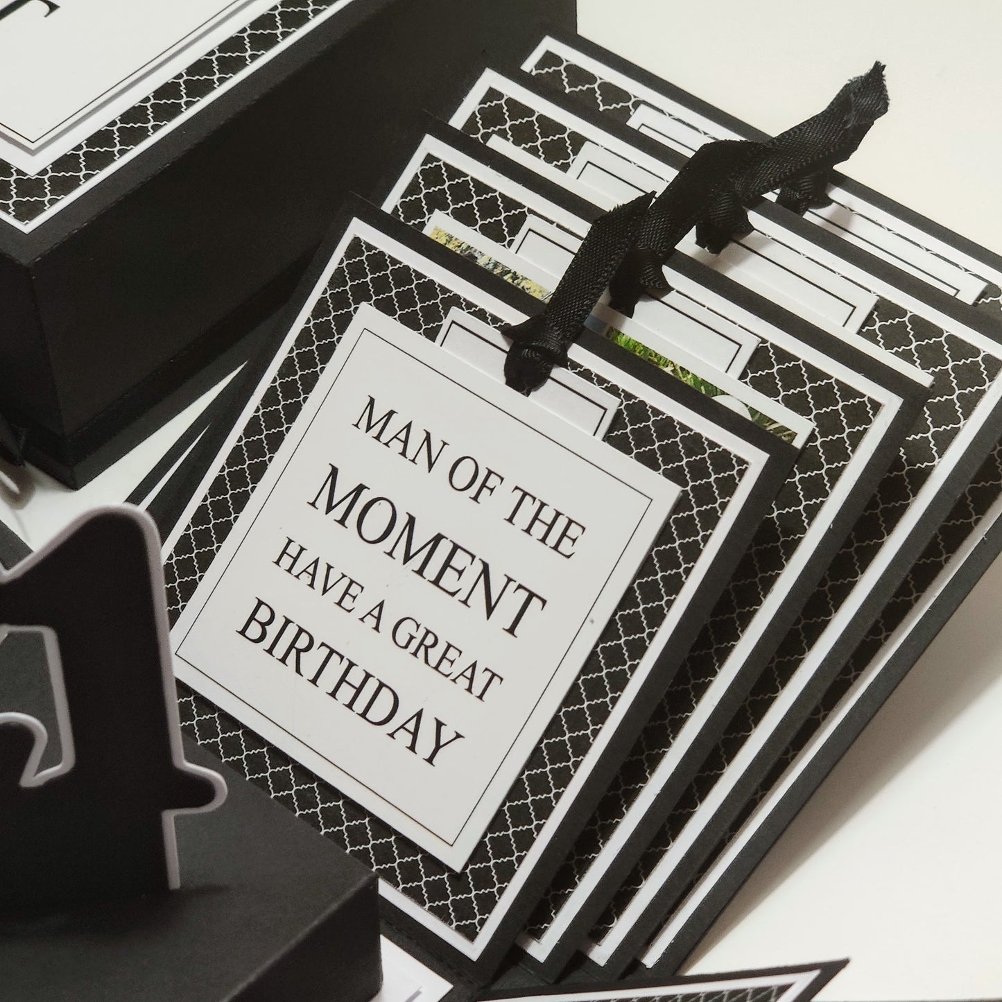 Exploding Memory Photo Box - Surprise Gift - Keepsake Album Box features a monochrome geometric pattern, unfolds into a cross-shaped layout with ribbon-secured photo slots and a central compartment for mementoes.