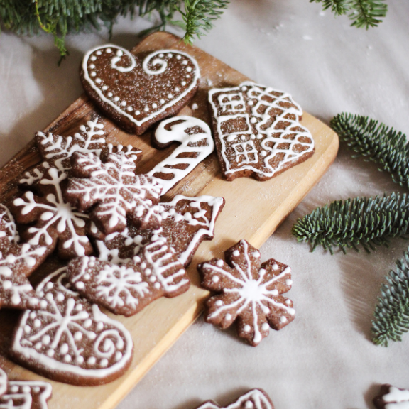 Decorative gingerbread cookies on a wooden board with Christmas decorations.