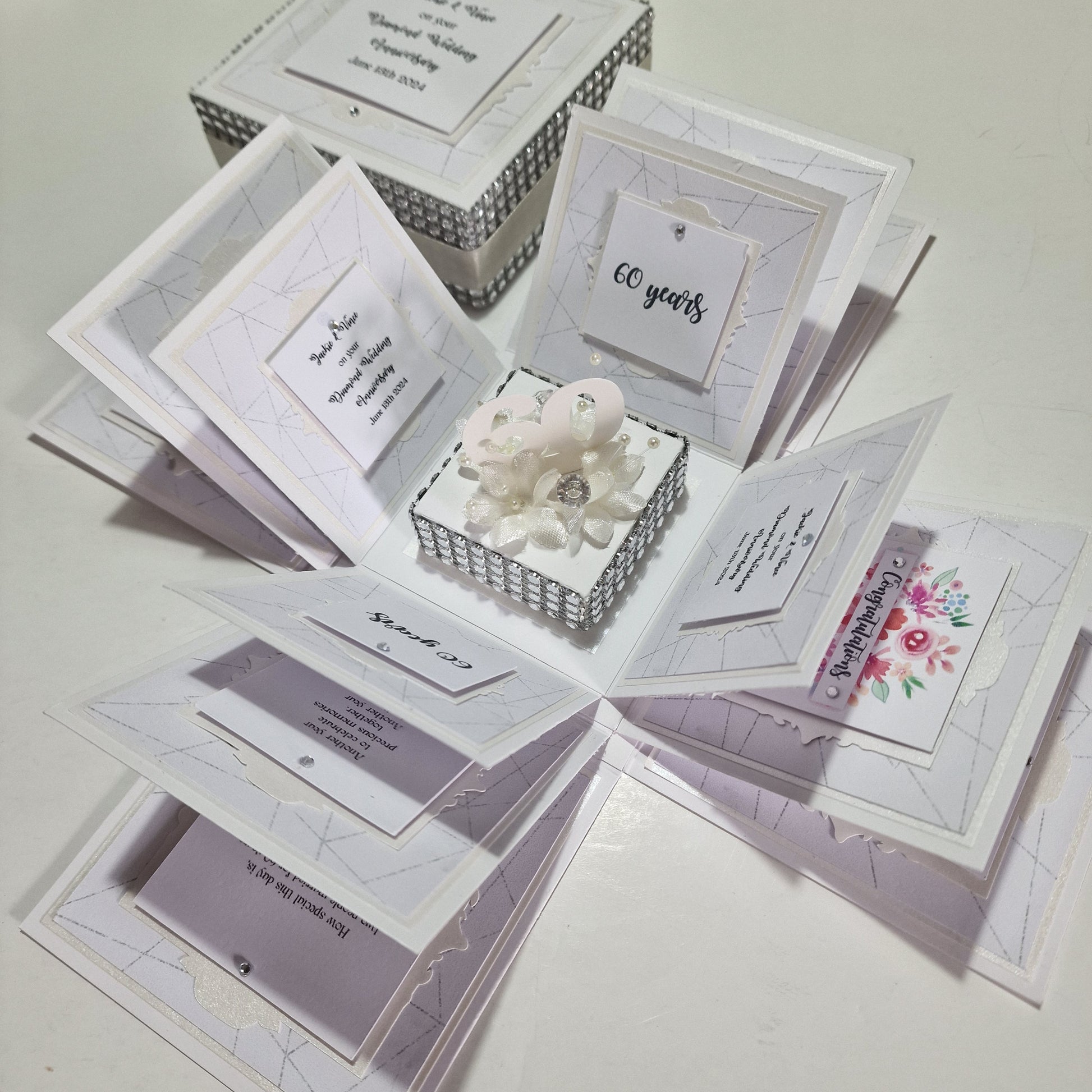 Diamond Wedding Anniversary Exploding Box showcasing a closed white box with intricate floral and pearl accents, designed to elegantly unfold revealing personalized, celebratory messages for a 60th anniversary.