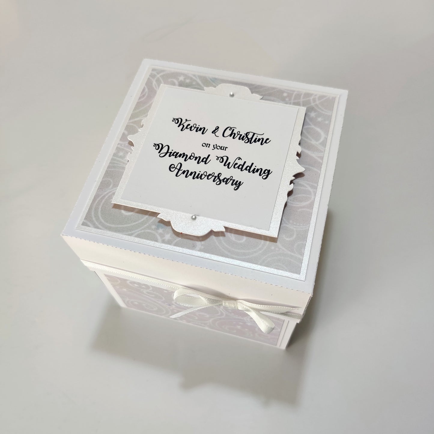 Diamond Wedding Anniversary Exploding Box featuring a white and silver design with a white ribbon bow, unfolds to reveal personalized messages, perfect for celebrating 60 years of love and commitment.