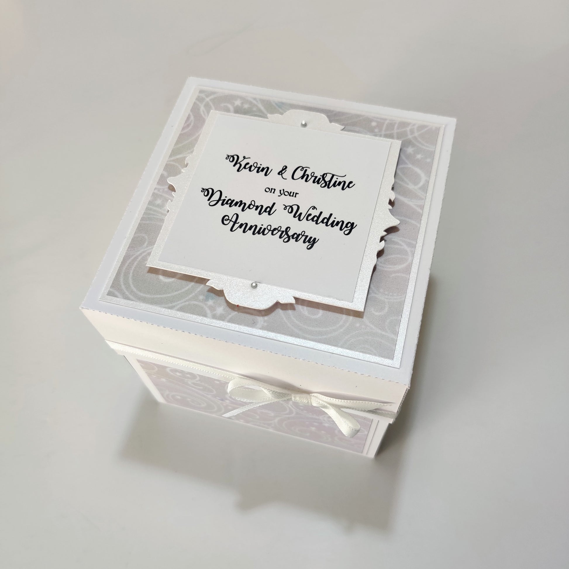 Diamond Wedding Anniversary Exploding Box featuring a white and silver design with a white ribbon bow, unfolds to reveal personalized messages, perfect for celebrating 60 years of love and commitment.