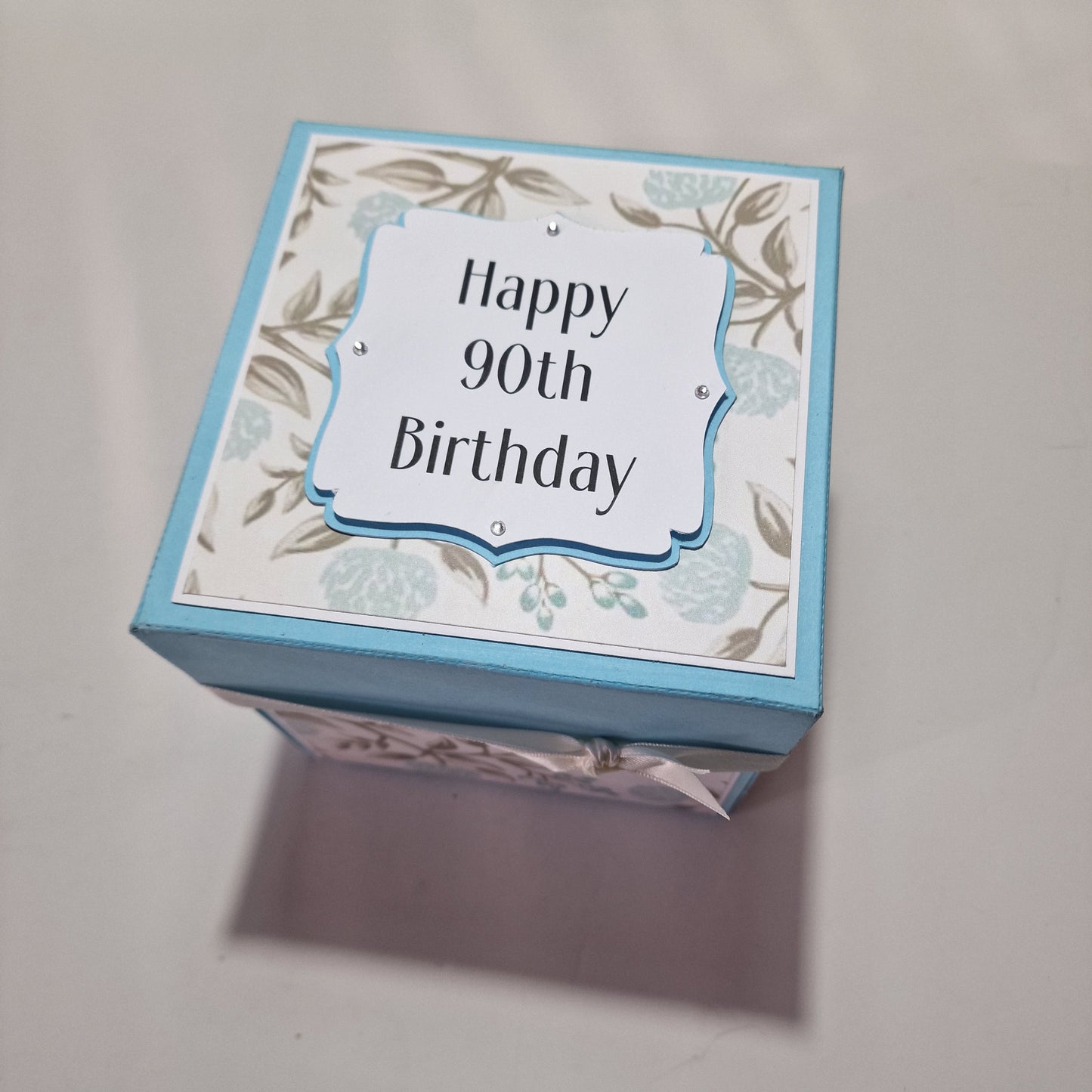 Pastel Blue Florals Birthday Celebration Pop-Open Box Card featuring intricate floral patterns and designed to open up, revealing a festive surprise. Ideal for adding a special touch to birthday celebrations.