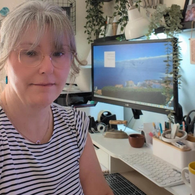 Woman sitting at a desk with a computer monitor displaying a scenic image