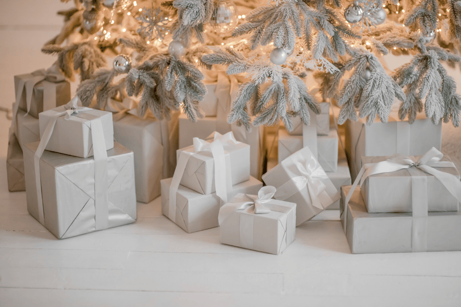 Silver Christmas presents under a decorated tree with lights.