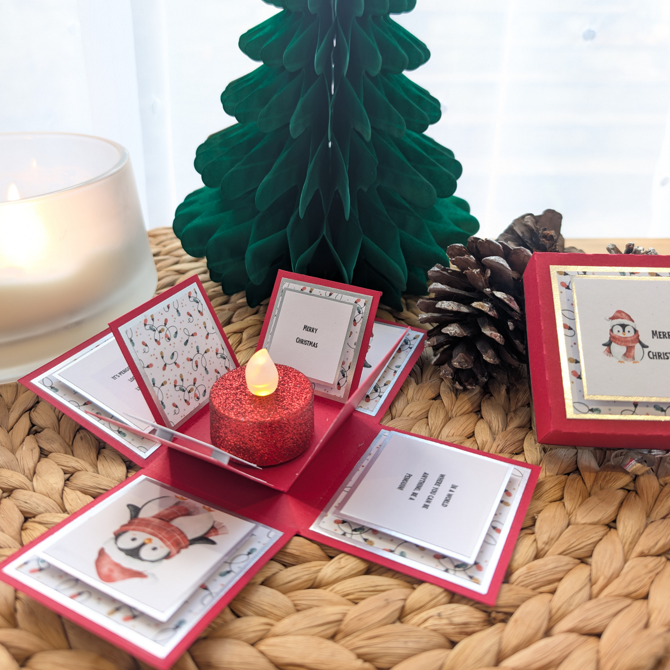Frosty The Penguin Christmas Box Card features a festive pop-up design with a penguin in a Santa hat, revealing holiday messages and a glittery LED candle centerpiece. Perfect for Christmas cheer.