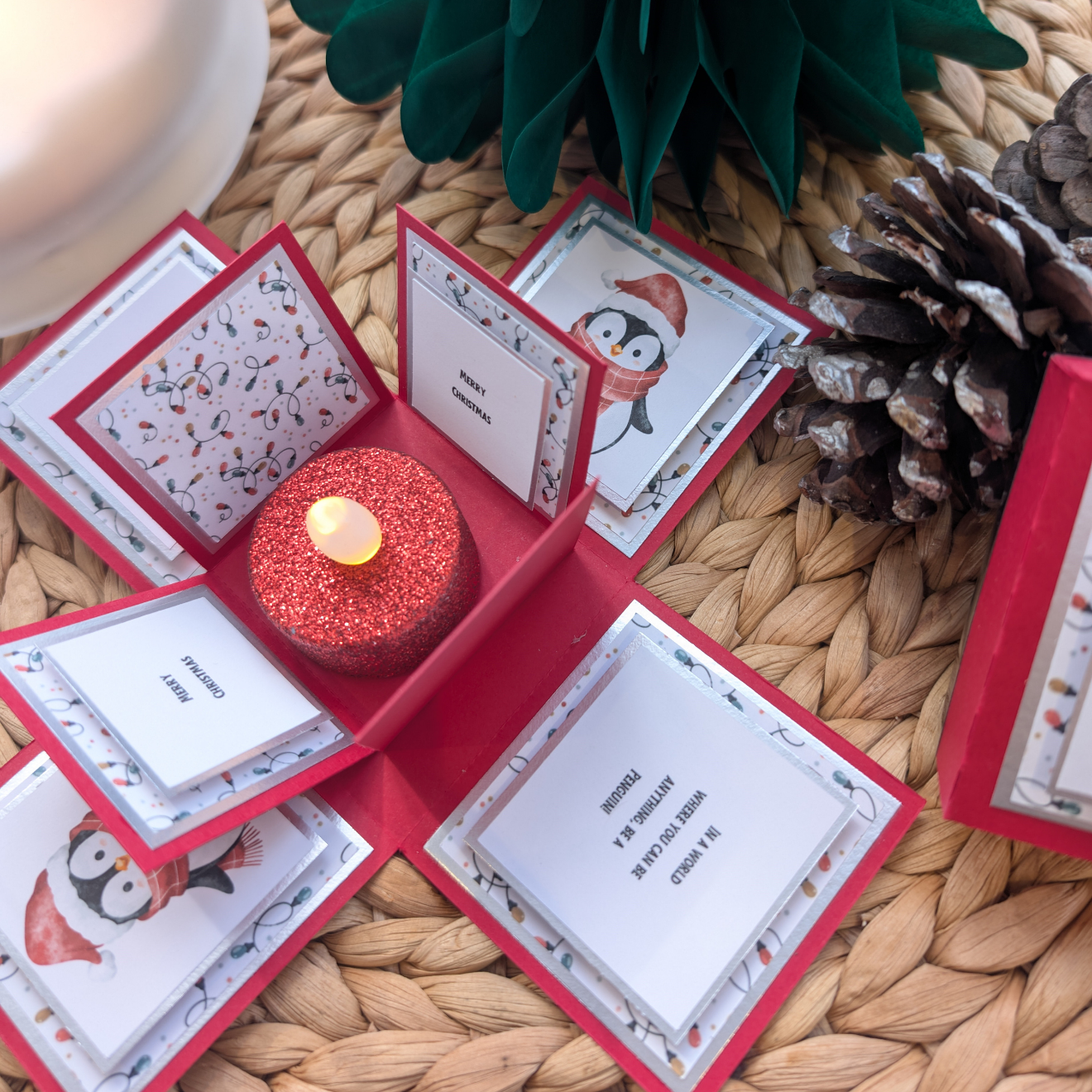 Frosty The Penguin Christmas Box Card: A festive pop-up greeting featuring a penguin theme, holiday messages, patterned panels, and a glittery red LED candle centerpiece, perfect for a heartwarming Christmas surprise.