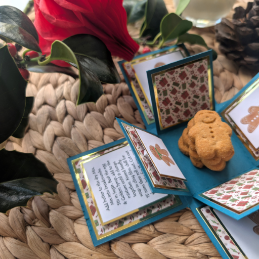 Exploding Christmas Box Card with Gingerbread Recipe, a festive keepsake featuring patterned panels and gingerbread cookies, set among holly and pine cones for a cozy holiday atmosphere.