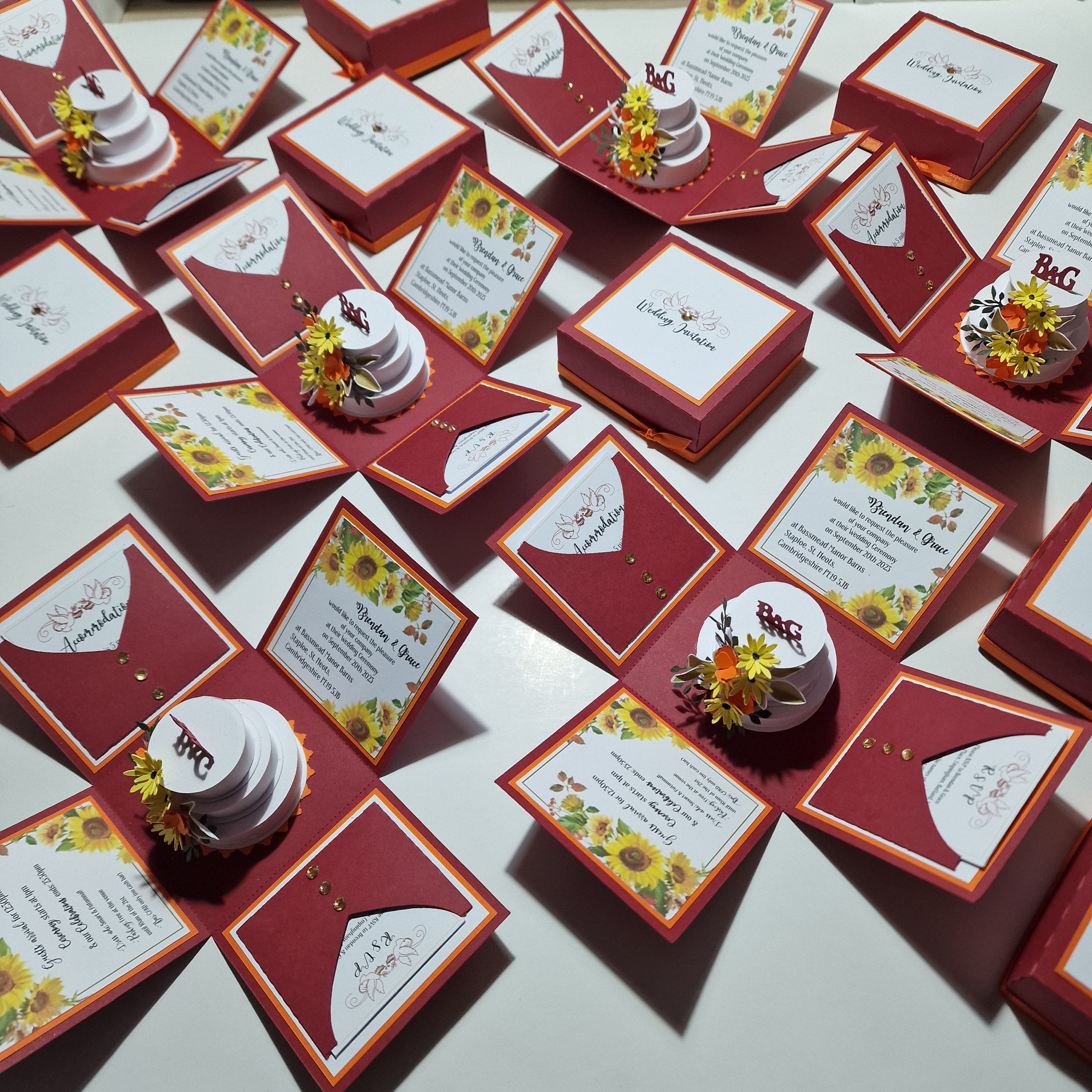 Custom Designed & Built Exploding Wedding Invitation Boxes featuring intricate detailing with flowers on top, elegantly tied with ribbons, perfect for luxury invites and bespoke wedding stationery.