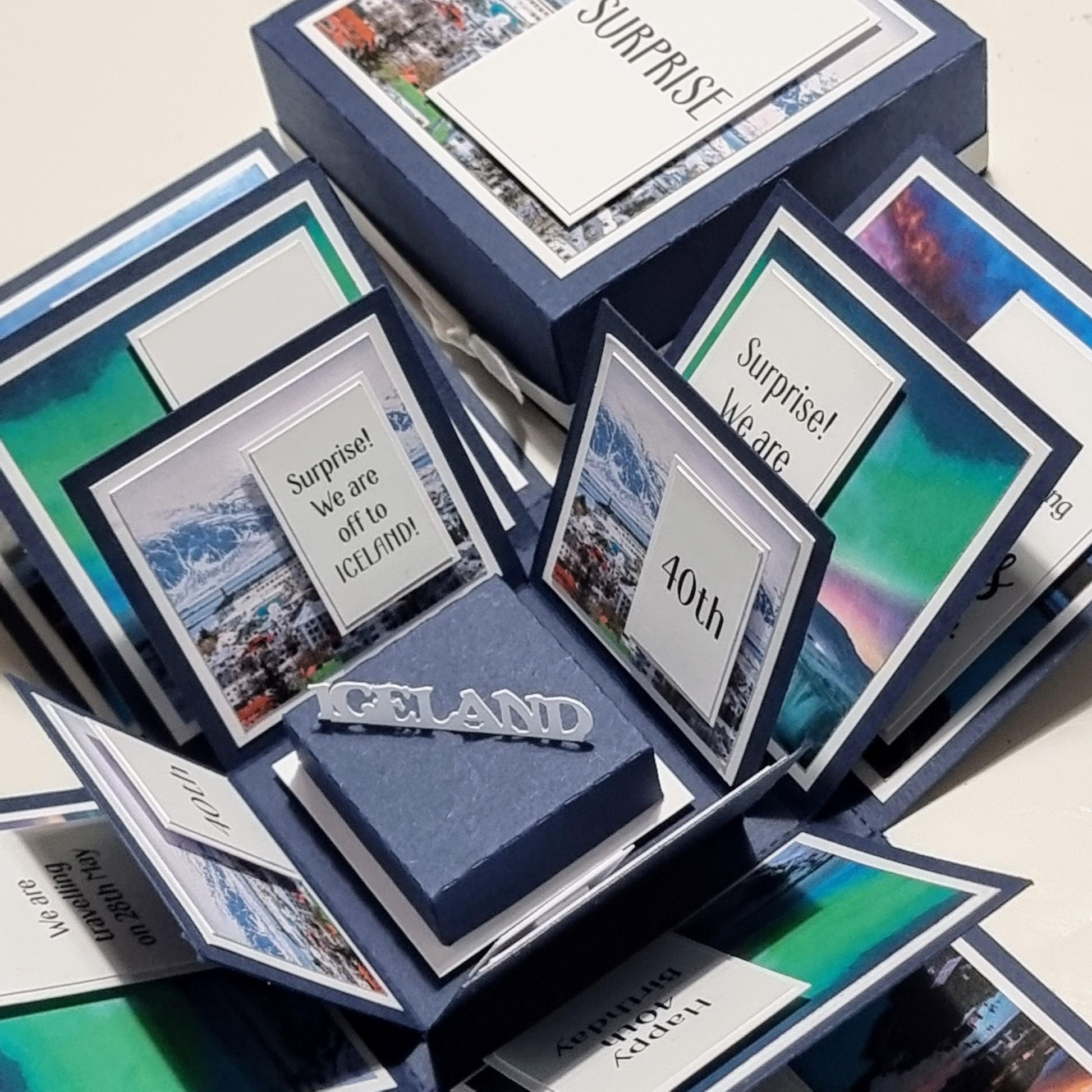 Exploding Occasions Box - Trip Reveal ICELAND: A detailed surprise box featuring Iceland-themed landscape and verse panels, with space for personalized trip details, names, and messages. Ideal for special celebrations.