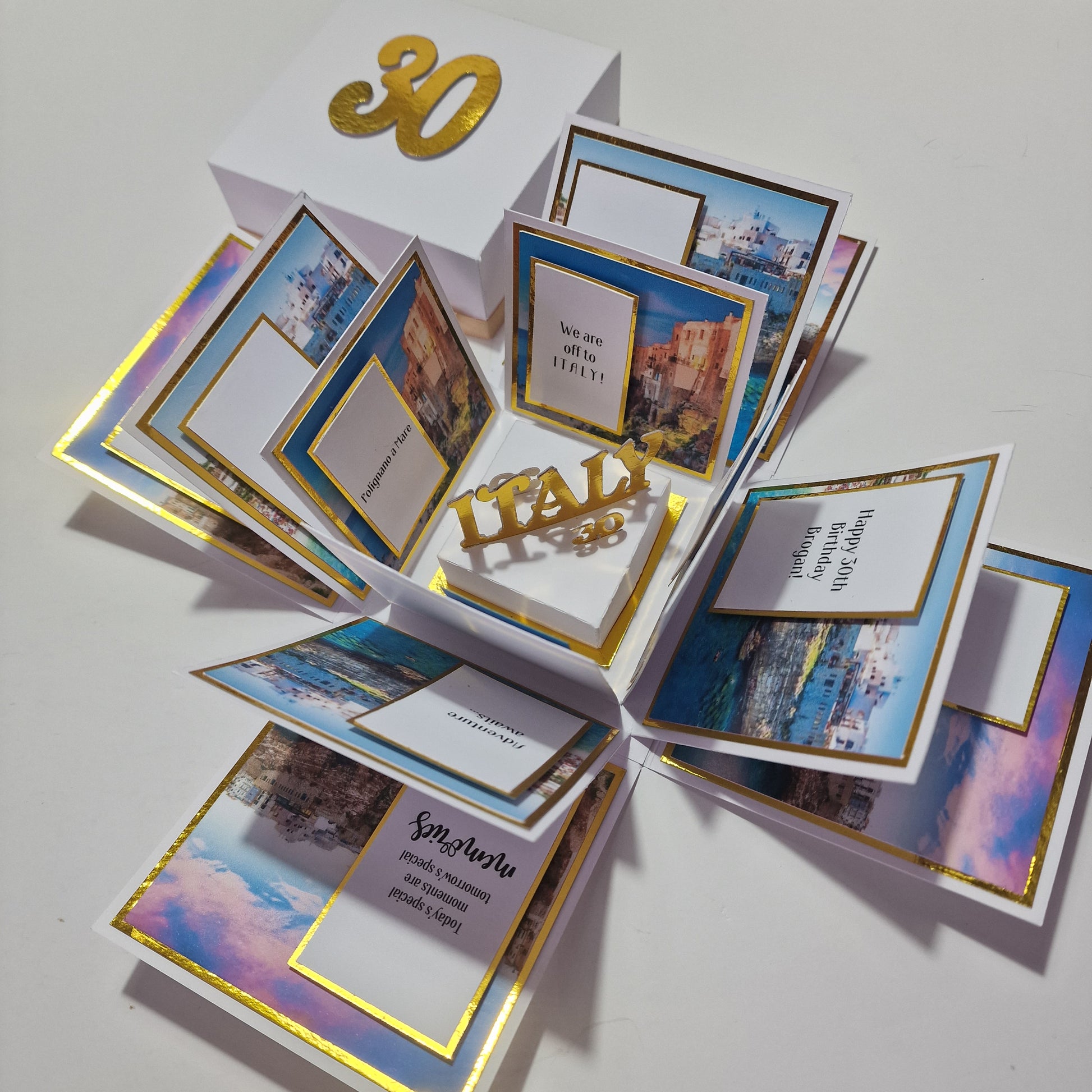 White paper box with images of italian cities on gold mounts