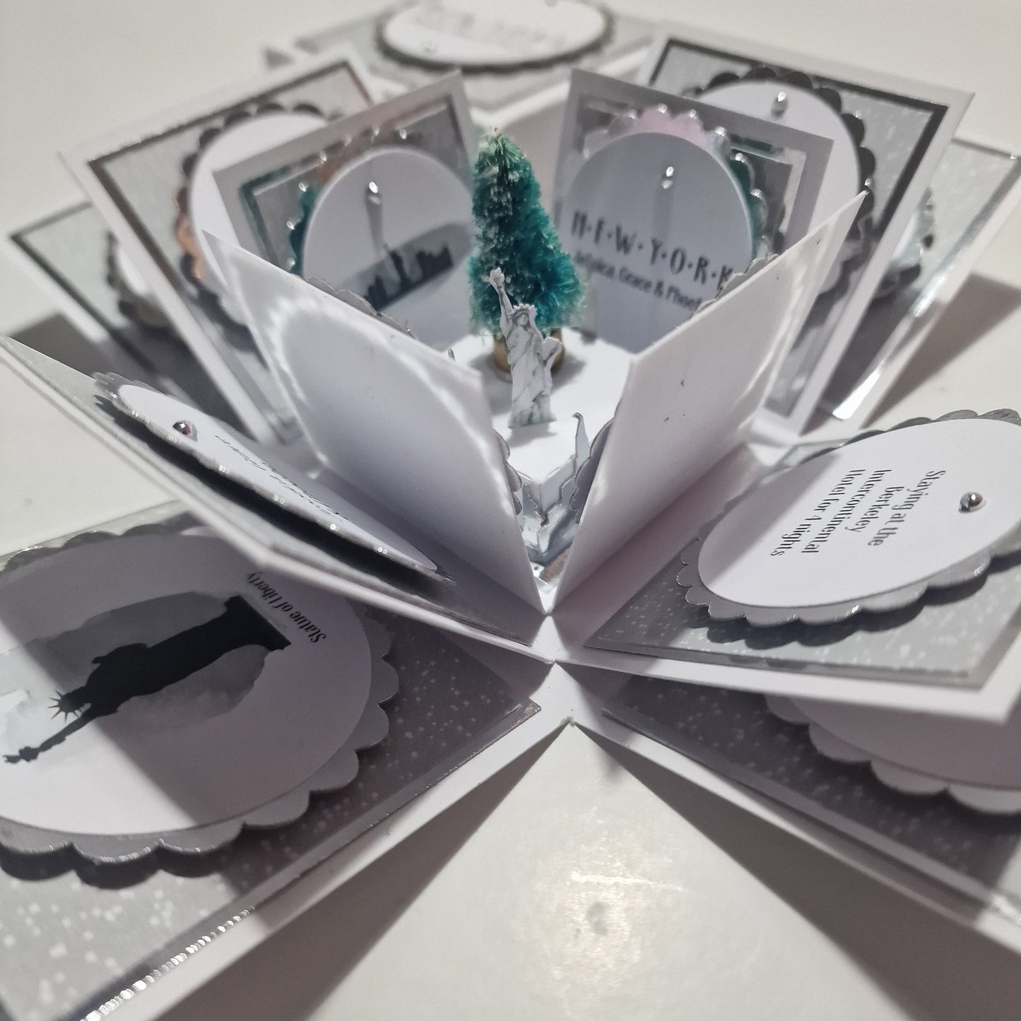 White & Silver New York at Christmas Trip Reveal Exploding Occasion Box. Featuring snowy papers, iconic land marks, verses & messages. Personalised with names, dates & trip info