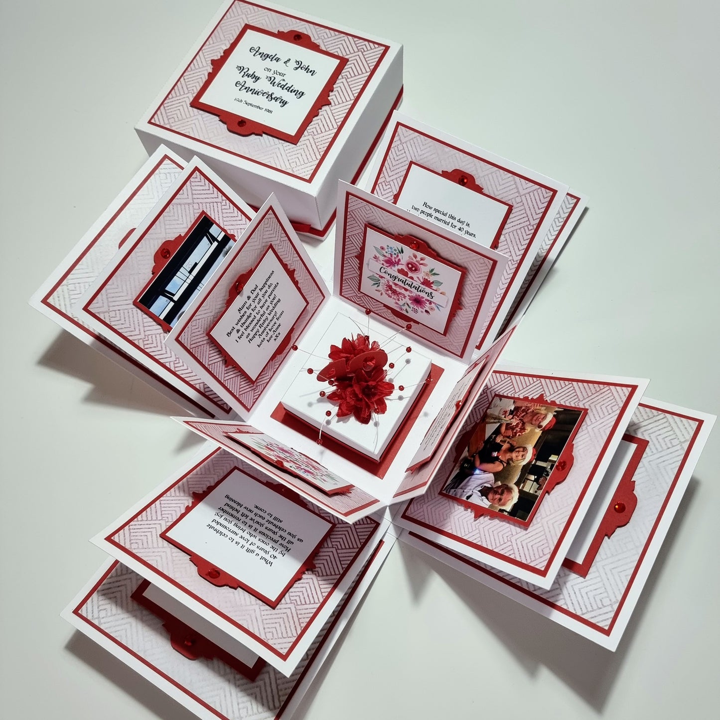 Ruby Wedding Anniversary Exploding Box featuring a white base and ruby-red accents, adorned with a red bow. Includes customizable panels with heartfelt messages and flower designs, perfect for celebrating four decades of love.
