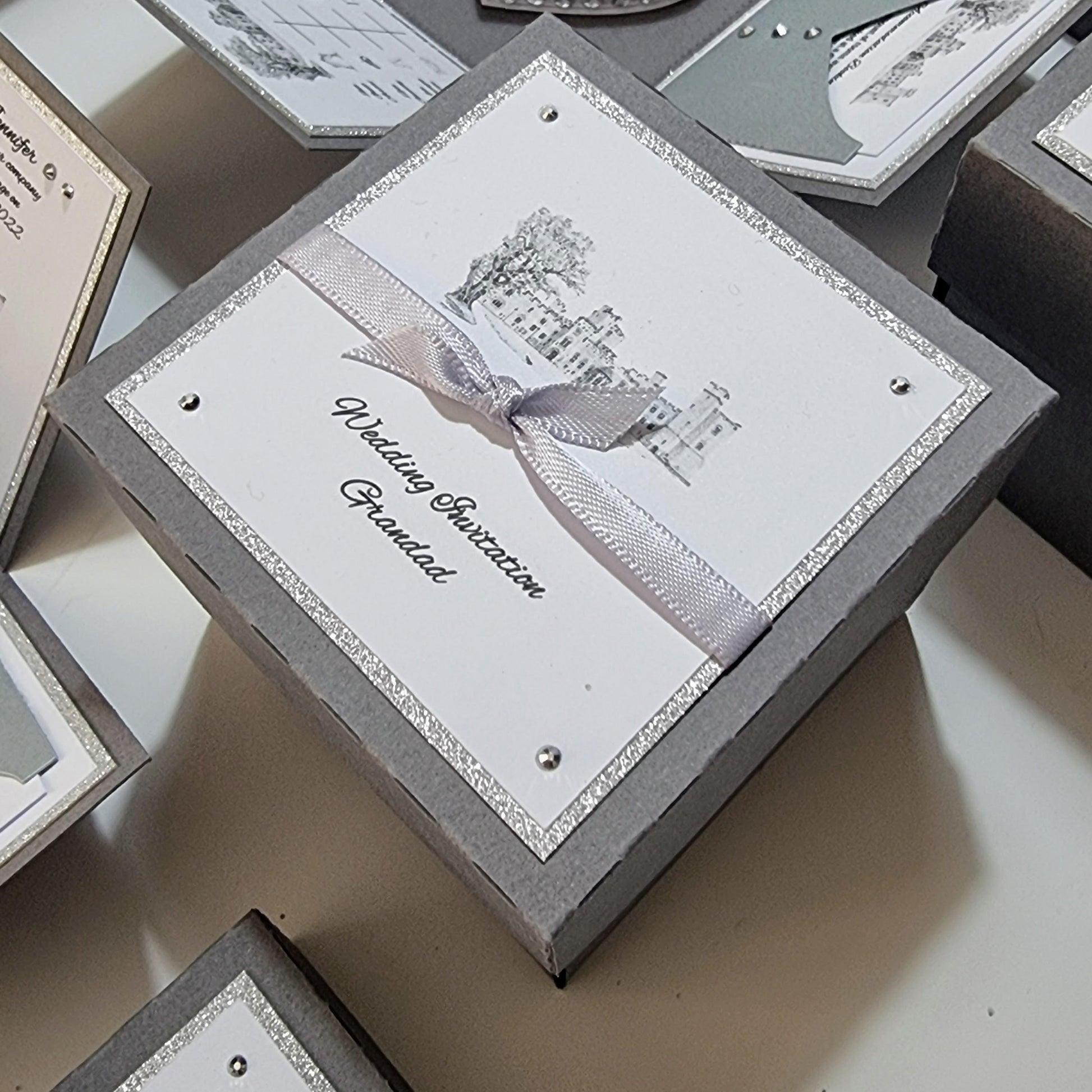 Illustrated Styled Exploding Wedding Invitation Boxes displaying intricate panels for invitation details, event timeline, and decorative elements like a heart-shaped cake with rings, embodying luxury and bespoke wedding stationery.