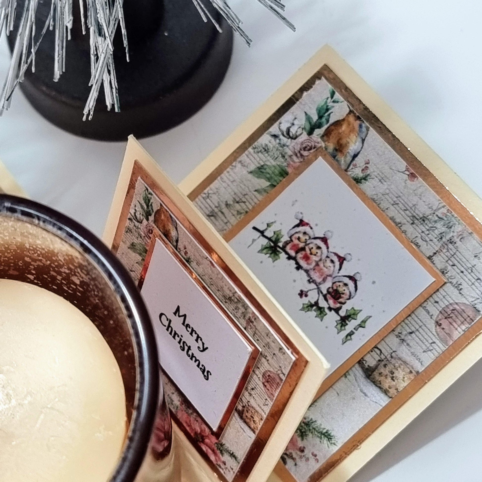 Rocking Robin Christmas Candle Box featuring a set of festive cards with Christmas Robins, accompanied by a votive candleholder and scented candle, elegantly displayed next to a candle.