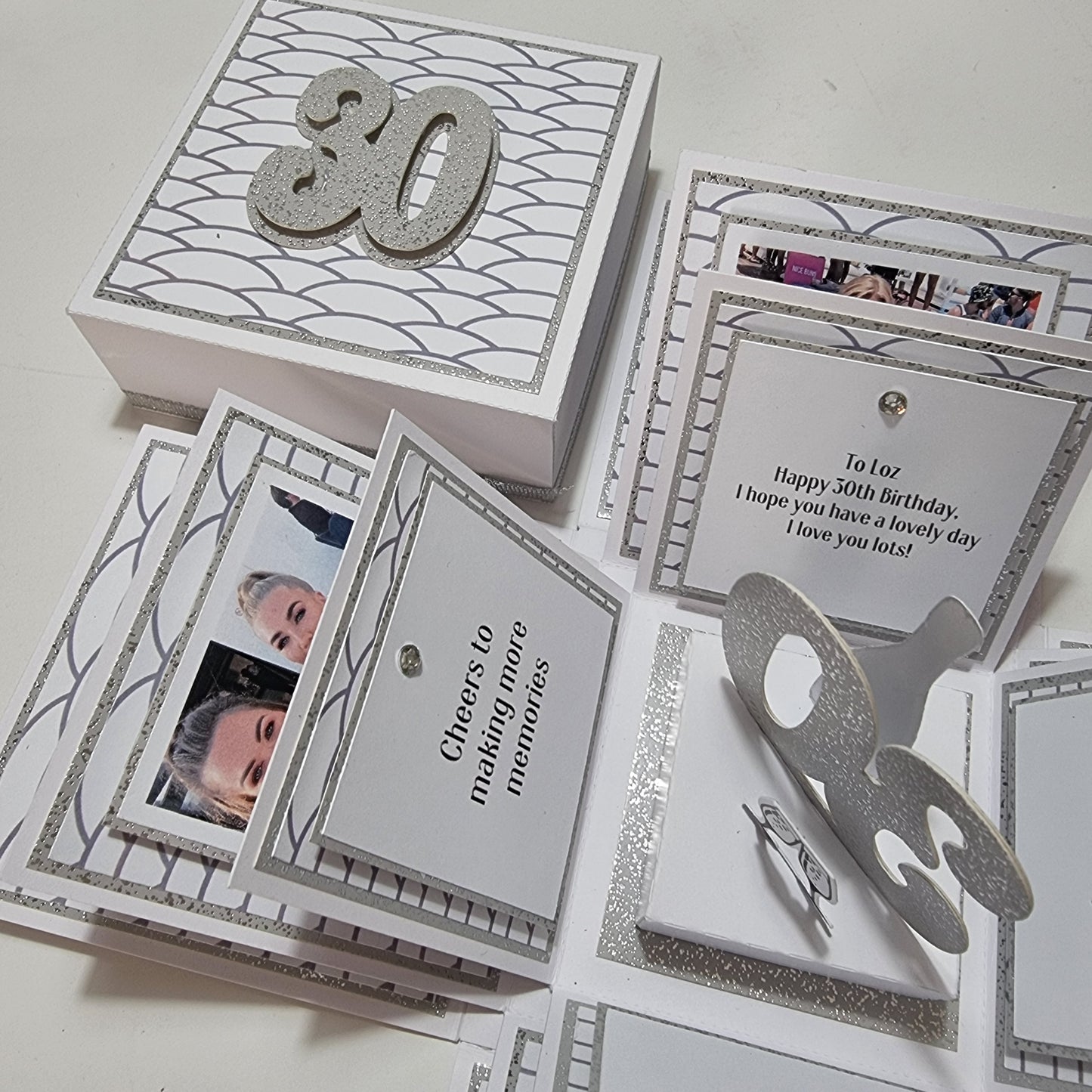 Exploding Memory Photo Box - Silver Scalloped Waves, featuring elegant silver accents and a 30 champagne bottle centerpiece, surrounded by photo panels and heartfelt messages, perfect for significant celebrations.