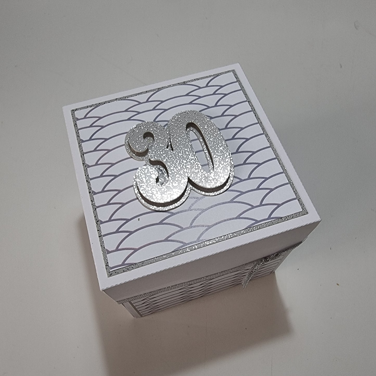 Exploding Memory Photo Box - Silver Scalloped Waves showcases a handcrafted box with elegant silver accents, unfolding to reveal photo panels and a central “30” champagne bottle cutout, perfect for milestone celebrations.