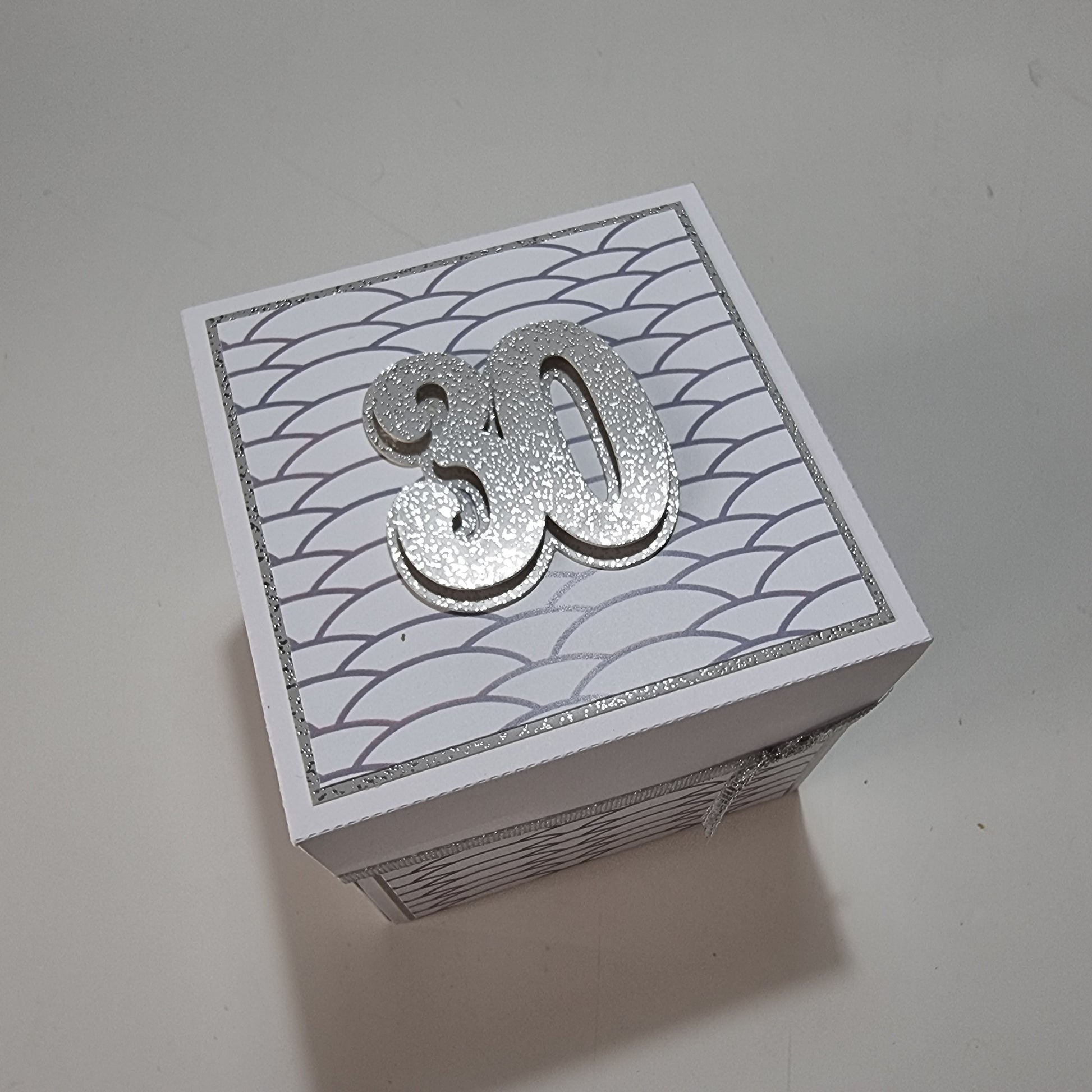Exploding Memory Photo Box - Silver Scalloped Waves showcases a handcrafted box with elegant silver accents, unfolding to reveal photo panels and a central “30” champagne bottle cutout, perfect for milestone celebrations.