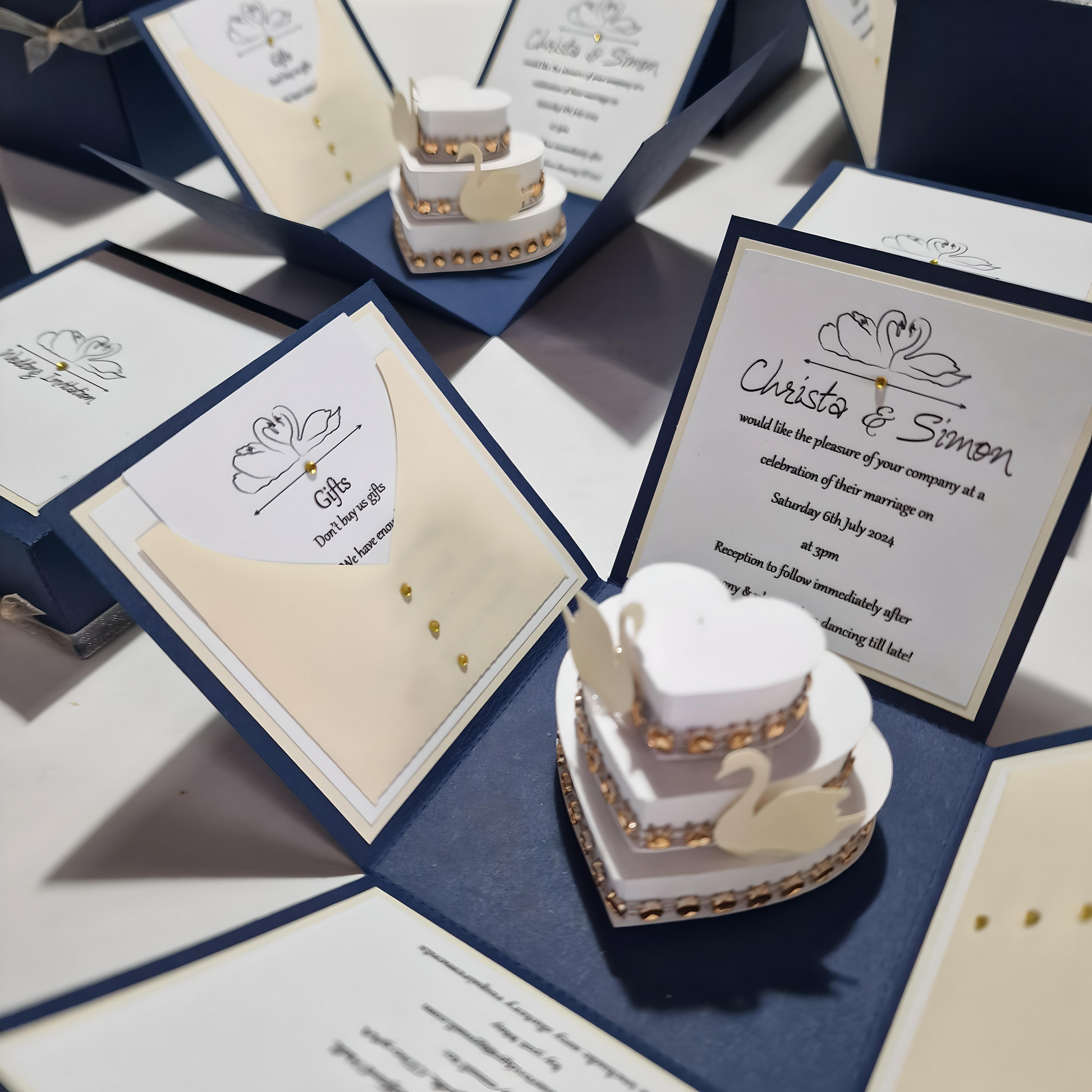 Swans Pocket Exploding Wedding Invitation Boxes featuring a heart-shaped cake with swans on top, surrounded by elegant invitation cards, symbolizing love and unity for weddings.