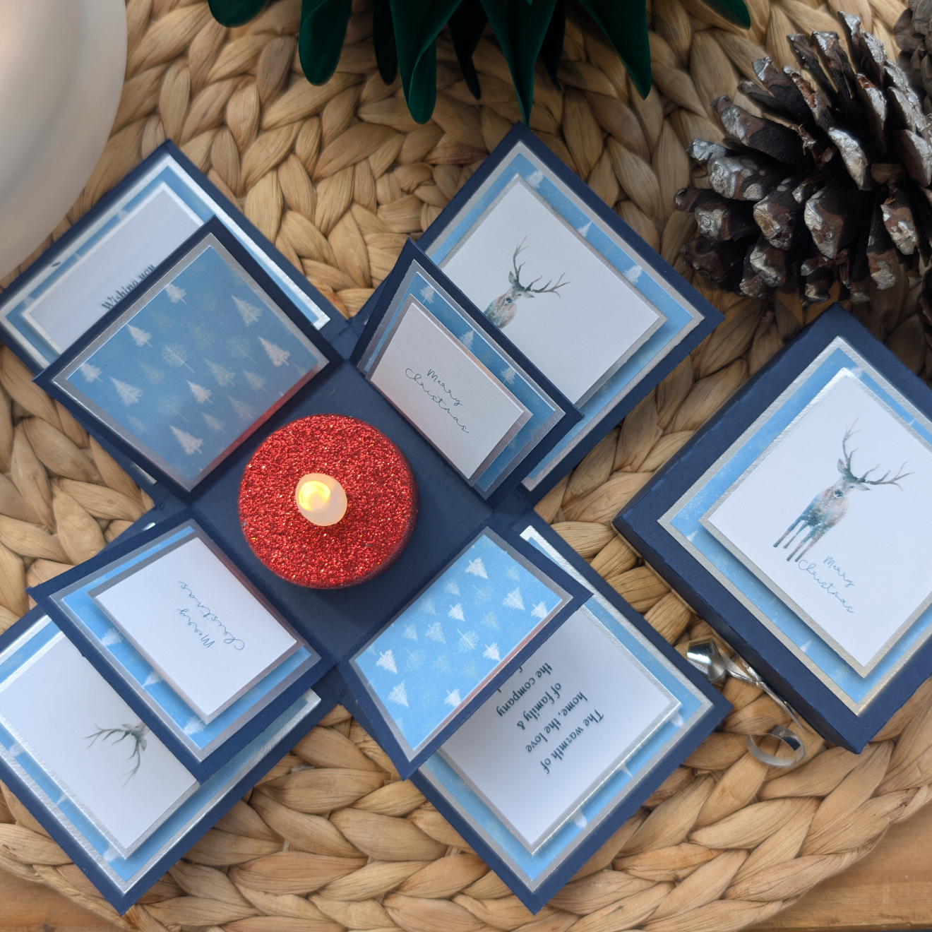 Winter Stagg Christmas Box Card – Festive Holiday Greeting with Pop-Up Design featuring layered flaps with Christmas trees, stags, holiday messages, and a central red glitter LED tealight for a magical touch.