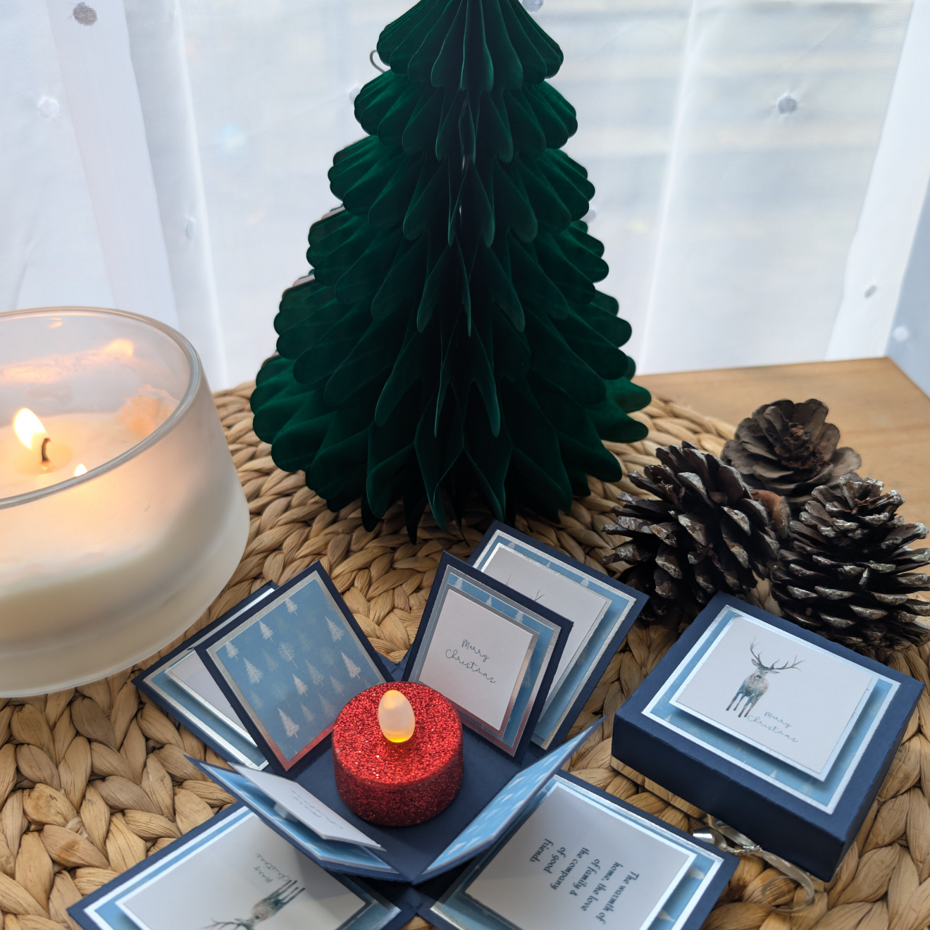 Winter Stagg Christmas Box Card – a festive pop-up design featuring layered panels with Christmas trees, a stag illustration, and “Merry Christmas” greetings, centered around a red glitter LED candle.