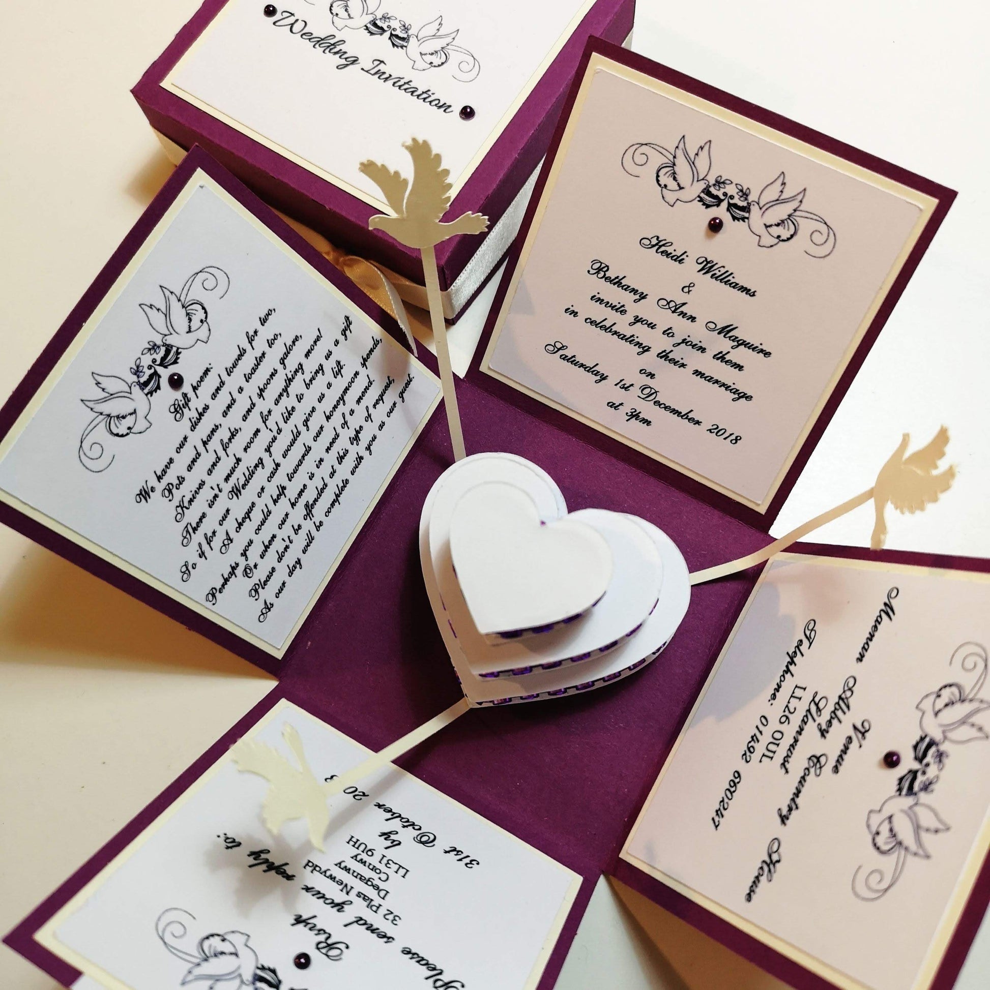 Hearts & Doves Range - In Purple & Cream. A totally unique 3'' Square Exploding Wedding Invitation Box featuring two fixed panels, One with Invitation details and the other with Venue details. There are also two waistcoat-styled pockets with pull-out panels containing Menu &amp; Menu Choices Cards plus RSVP Card &amp; Gift Poem. The centre of these boxes contains a three-tier Heart-shaped Wedding cake && floating doves