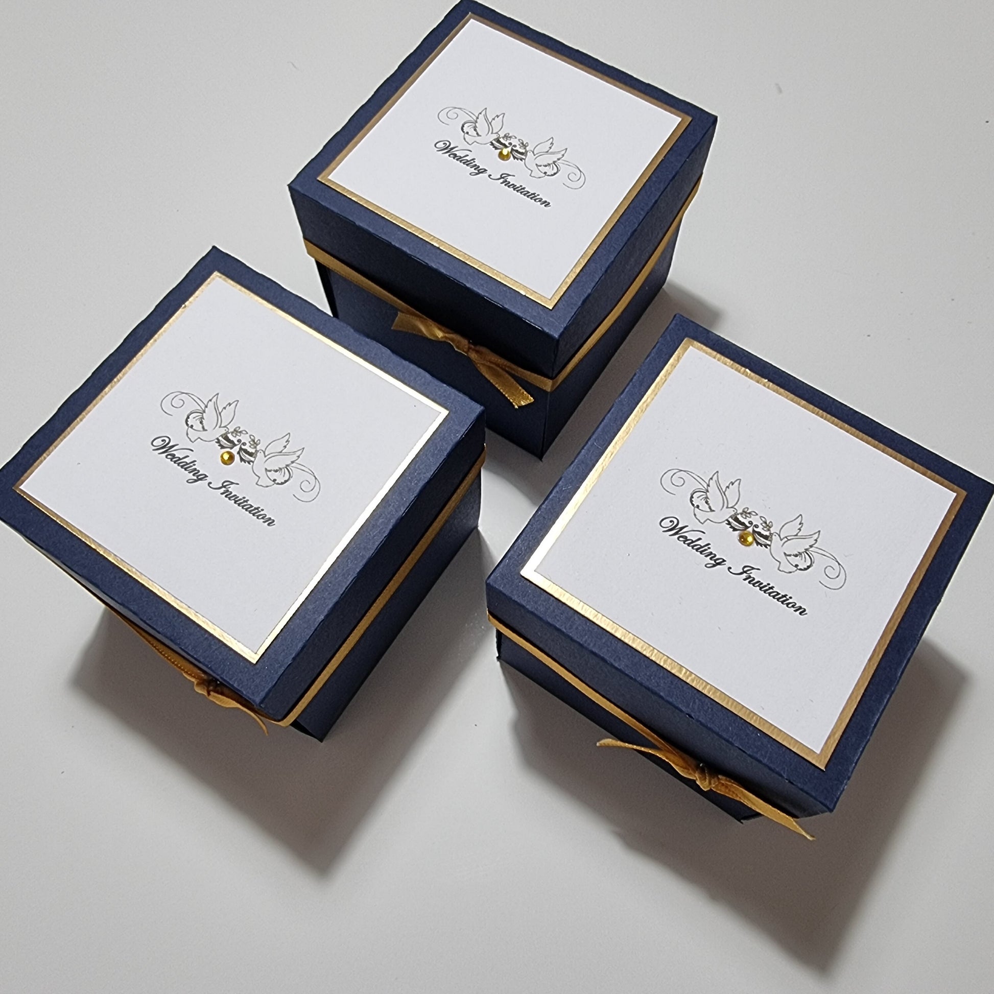 Hearts & Doves Range in Classic Navy Blue and Gold. Unique 3'' Square Exploding Wedding Invitation Box featuring two fixed panels, One with Invitation details and the other with Venue details. Gold gems.